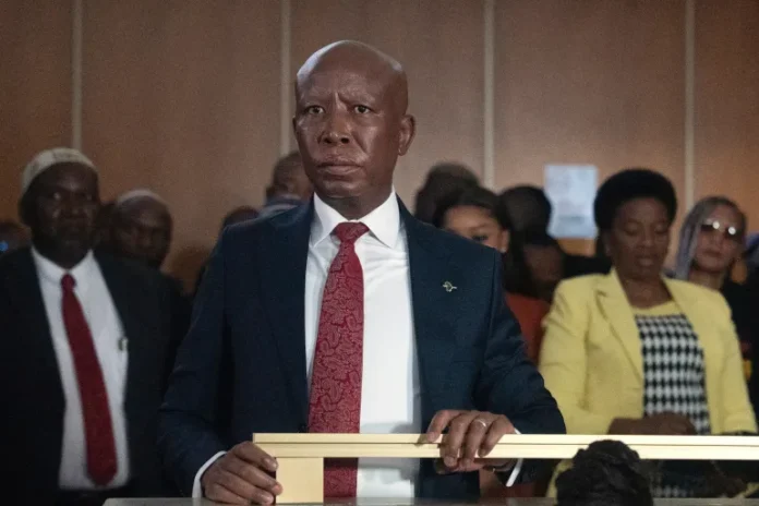 Julius Malema, Economic Freedom Fighters (EFF) party leader stands in the dock during a hearing in court, in East London, South Africa, Wednesday, April 15, 2026 [AP]