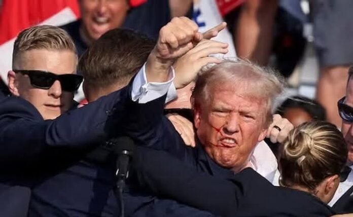  US President Donald Trump gestures with a bloodied face while he is assisted by US Secret Service personnel after he was shot in the right ear during a campaign rally at the Butler Farm Show in Butler, Pennsylvania, US, July 13, 2024.