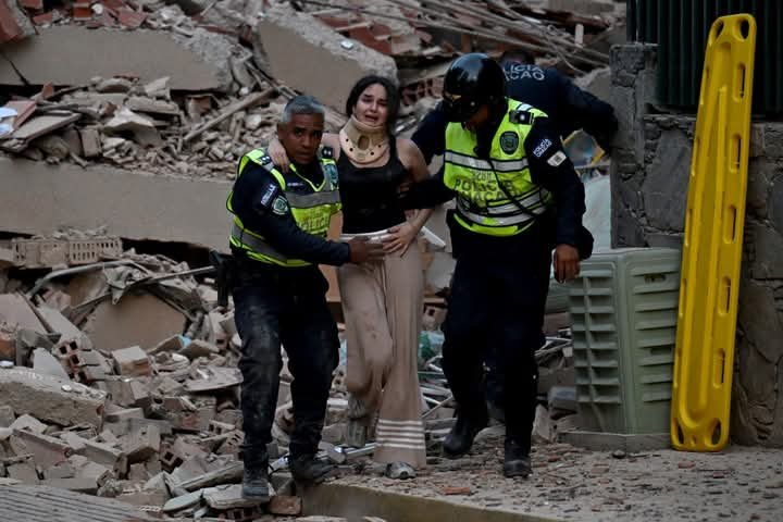 Emergency responders taking a woman to safety following quakes in Venezuela 