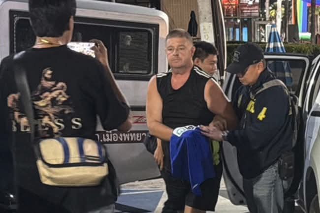 Simon Carman, 46, being escorted by Thai security personnel 